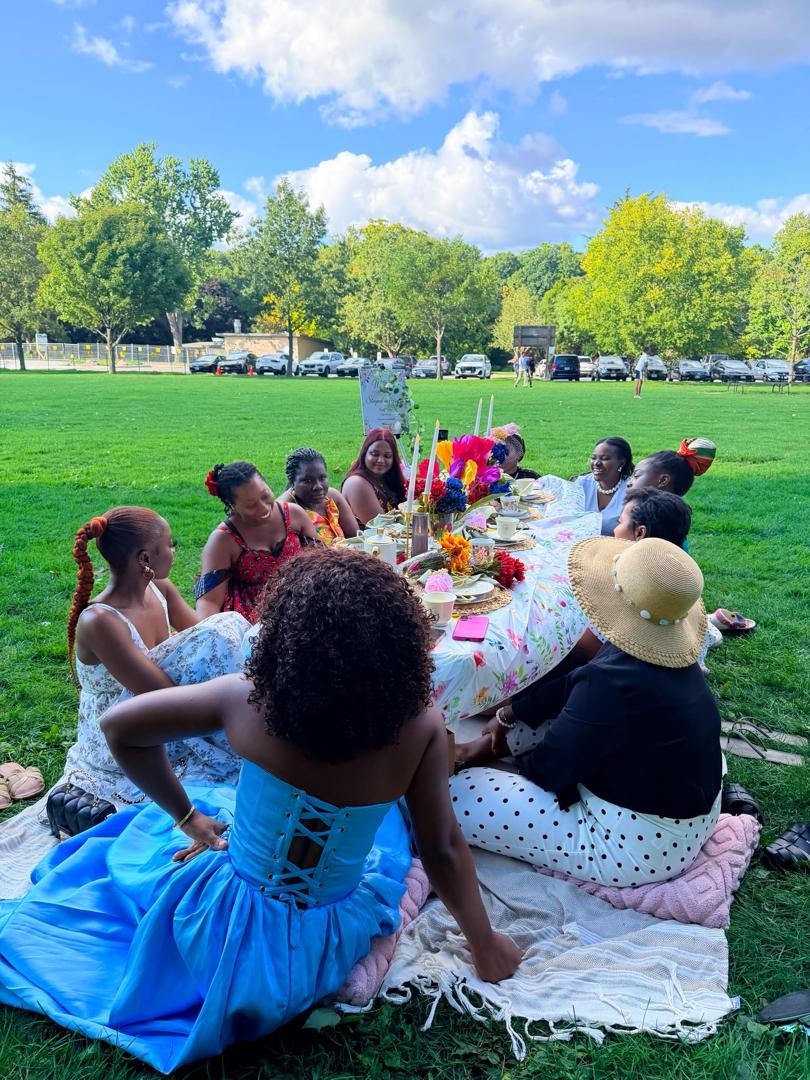 Members gathered around a tea-party table in the park